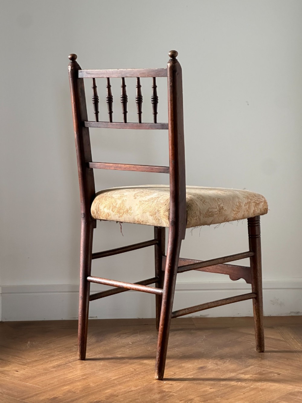 A 19th-century Sussex style side chair featuring turned spindles in the backrest, a dark wood frame, and a padded upholstered seat. View V