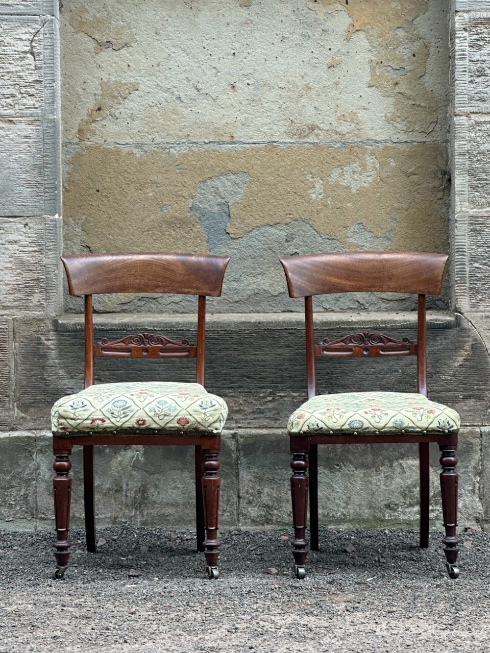 A pair of Scottish Regency mahogany side chairs with curved top rails, carved back splats, upholstered seats, and turned front legs on castors. View II
