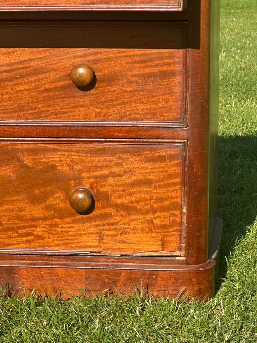 A small Victorian flame mahogany Scotch chest of drawers with two short over two long drawers, turned wooden knobs, and a serpentine top. View II