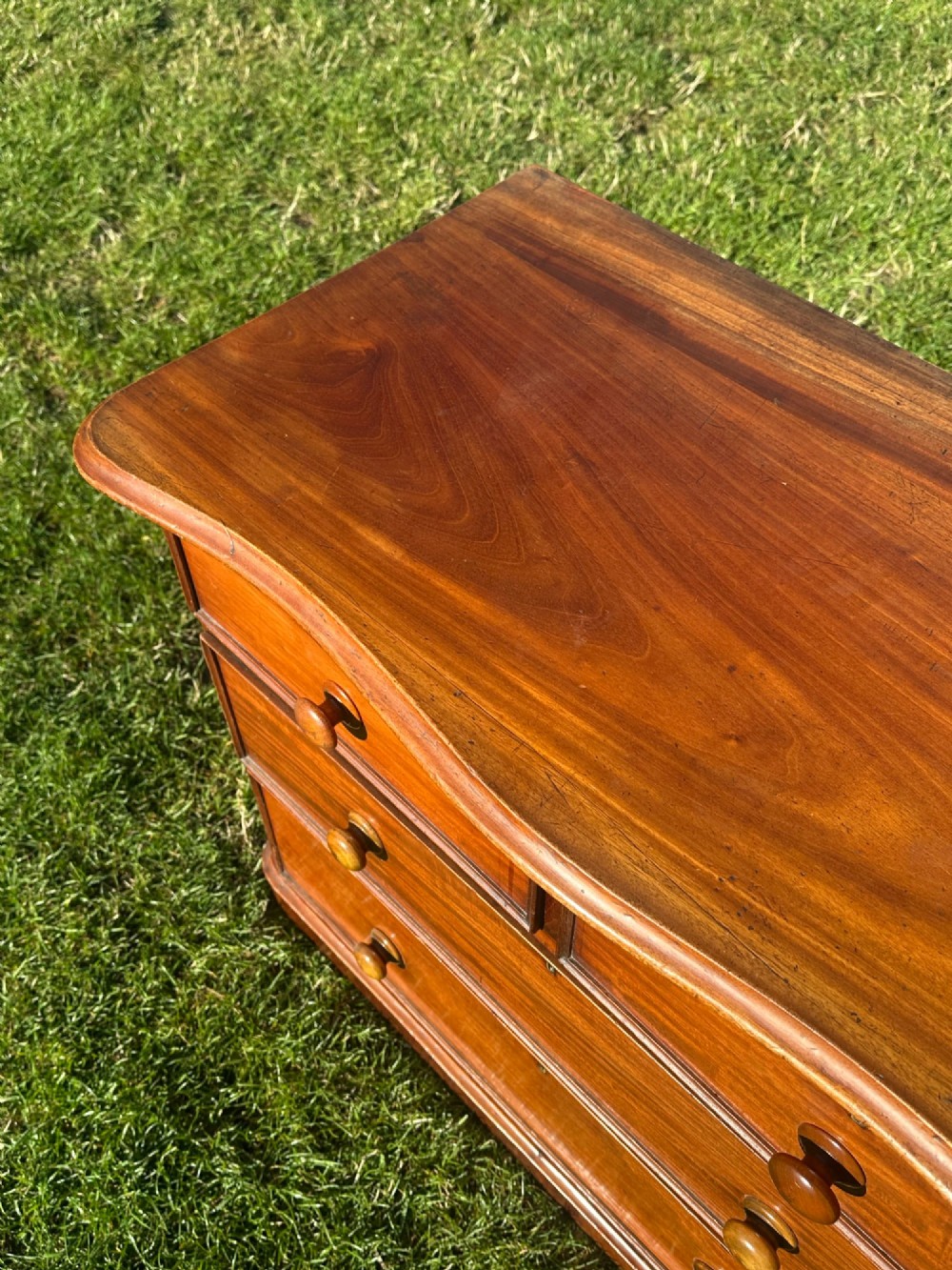 A small Victorian flame mahogany Scotch chest of drawers with two short over two long drawers, turned wooden knobs, and a serpentine top. View III