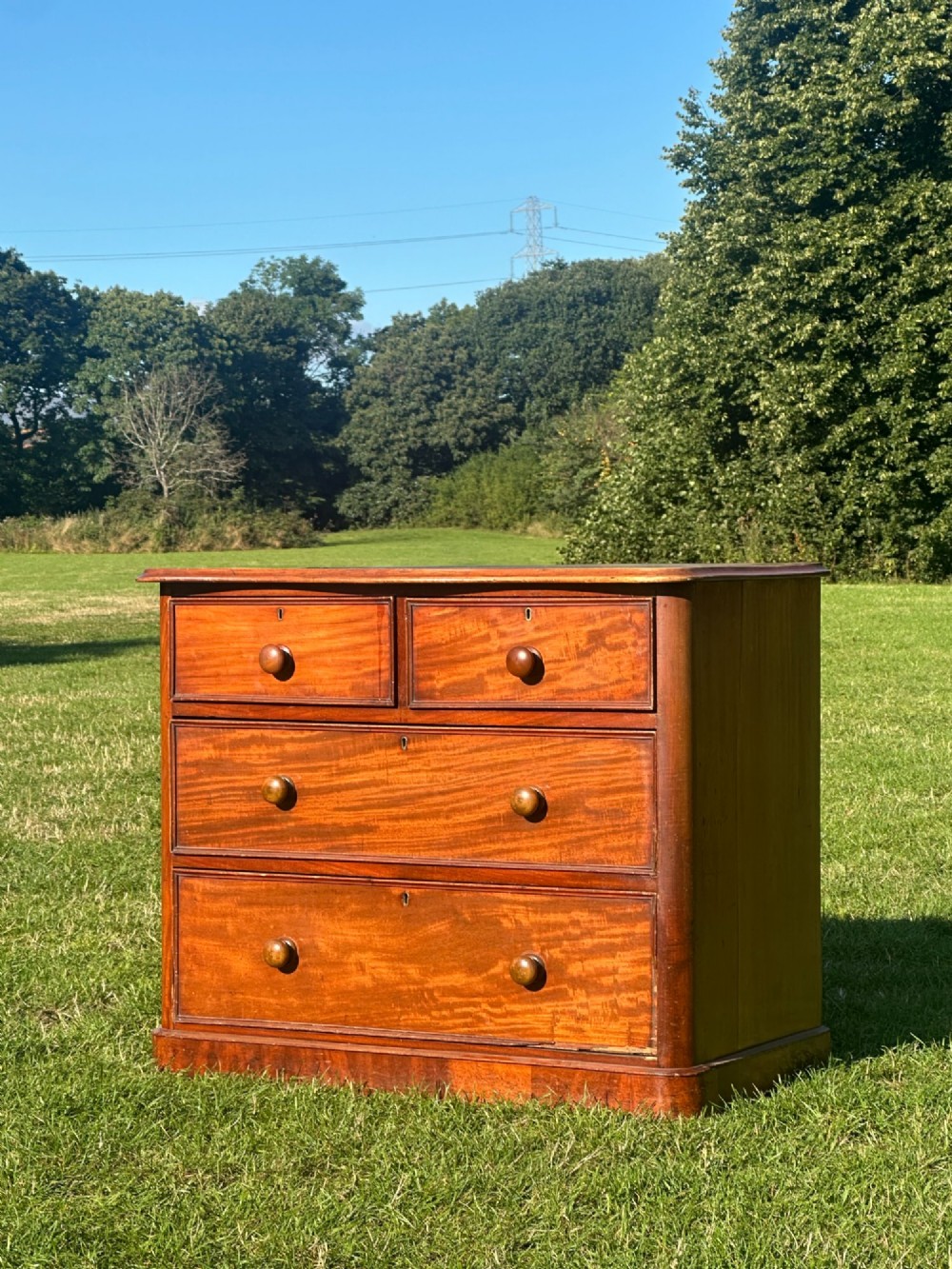 A small Victorian flame mahogany Scotch chest of drawers with two short over two long drawers, turned wooden knobs, and a serpentine top.