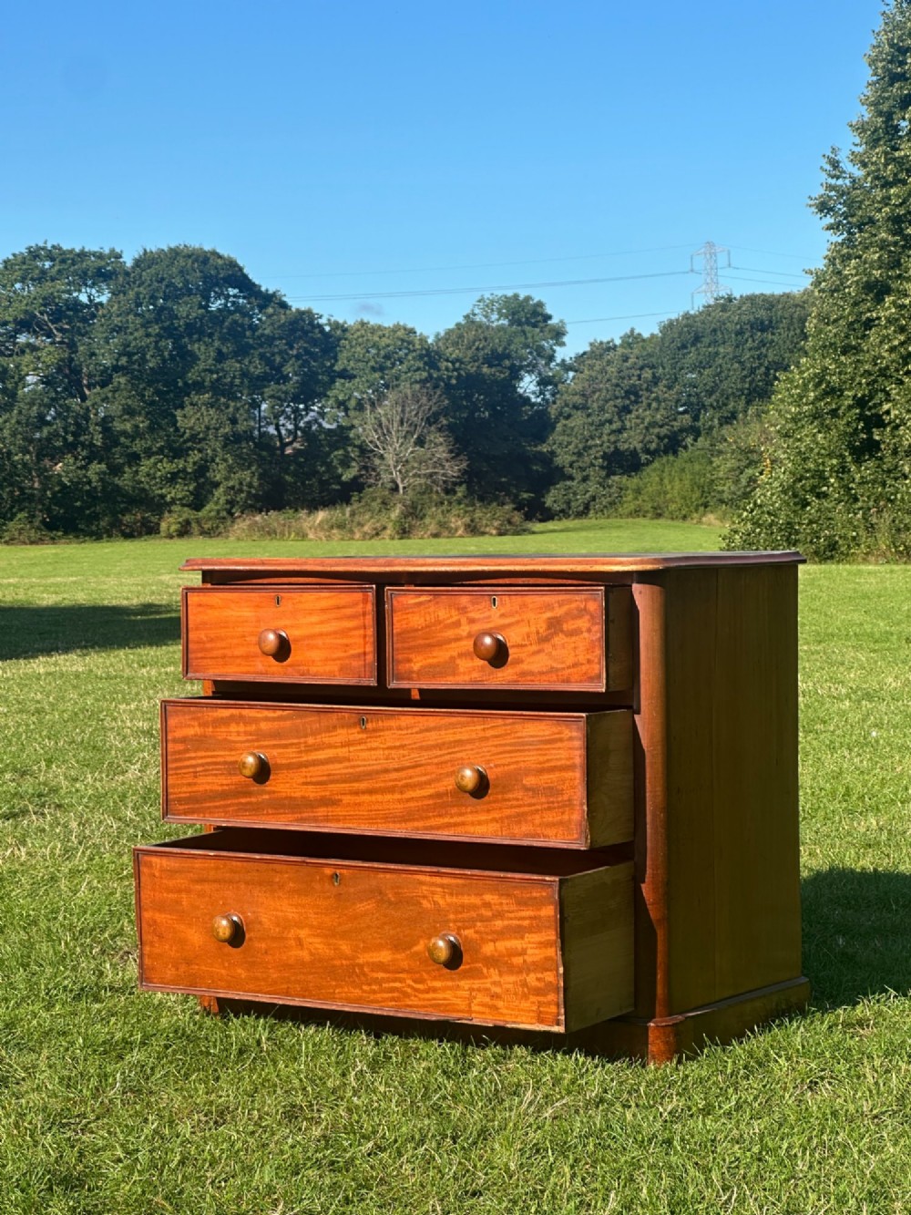 A small Victorian flame mahogany Scotch chest of drawers with two short over two long drawers, turned wooden knobs, and a serpentine top. View IV