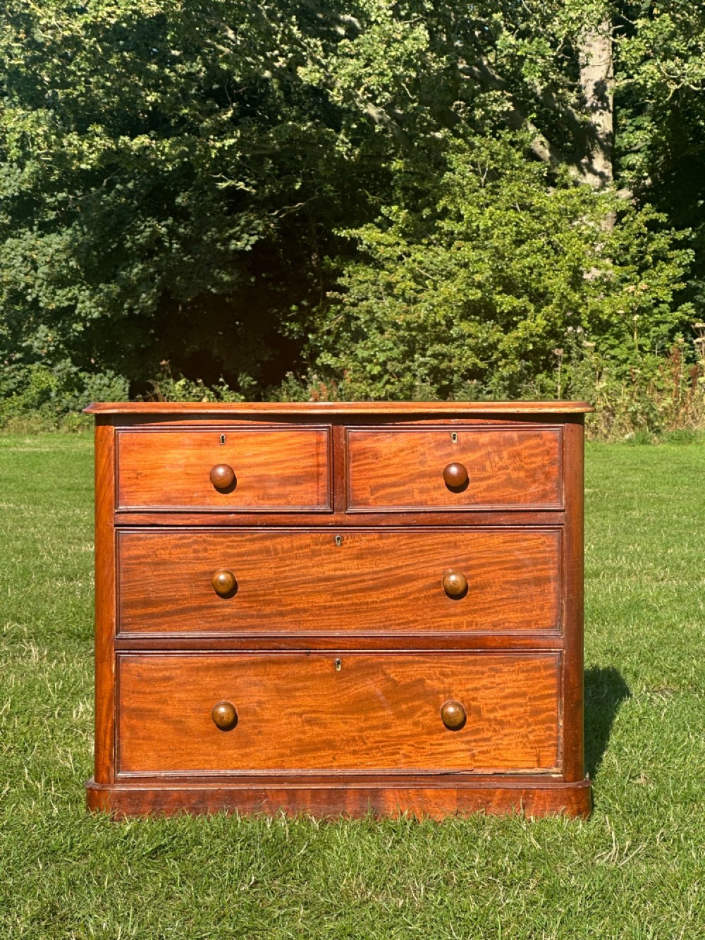 A small Victorian flame mahogany Scotch chest of drawers with two short over two long drawers, turned wooden knobs, and a serpentine top. View V