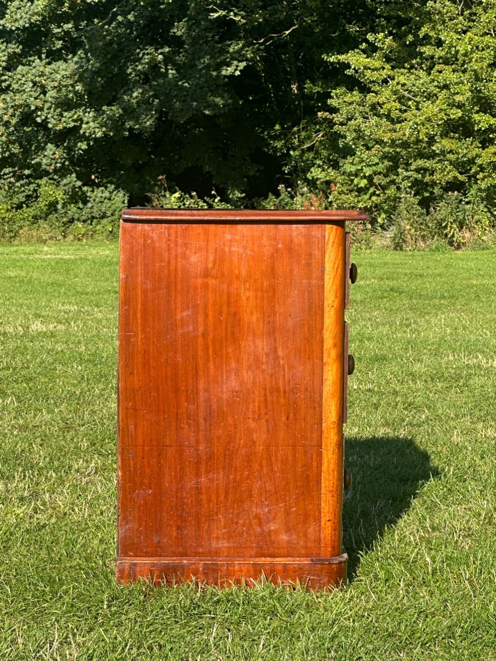 A small Victorian flame mahogany Scotch chest of drawers with two short over two long drawers, turned wooden knobs, and a serpentine top. View VIII