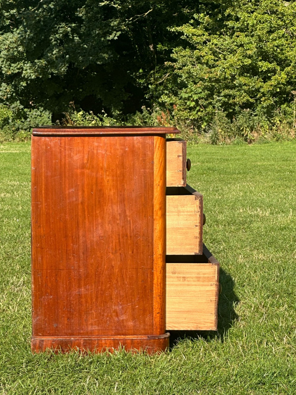 A small Victorian flame mahogany Scotch chest of drawers with two short over two long drawers, turned wooden knobs, and a serpentine top. View X