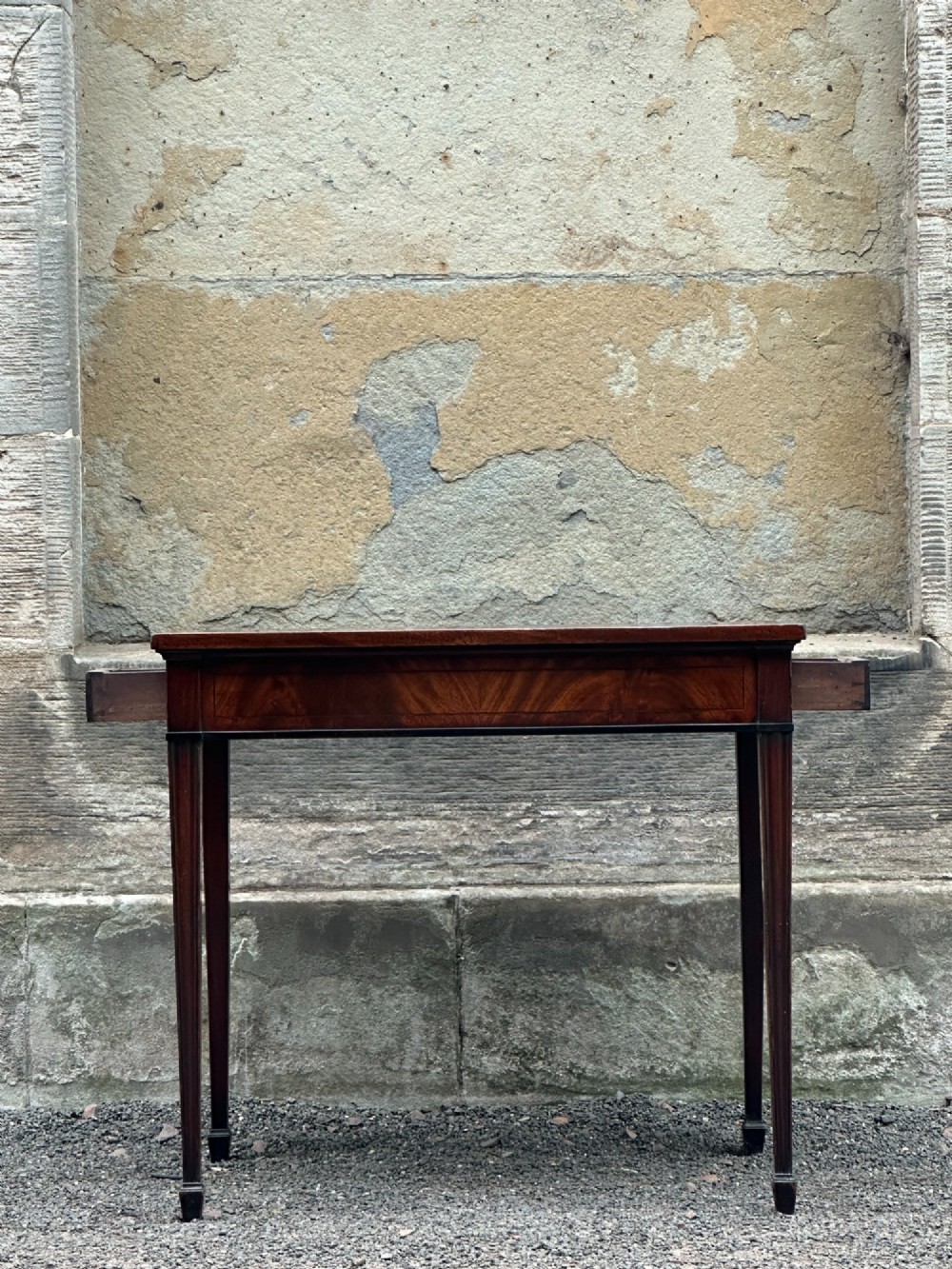 A George III mahogany side table with tapered legs, a flame mahogany veneered frieze, and a brass drawer pull. View III