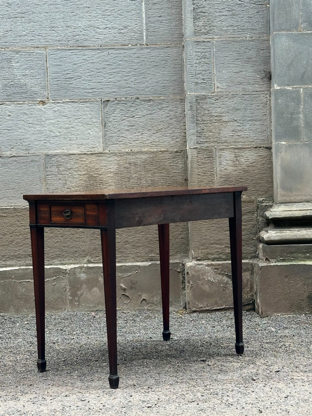 A George III mahogany side table with tapered legs, a flame mahogany veneered frieze, and a brass drawer pull. View VIII