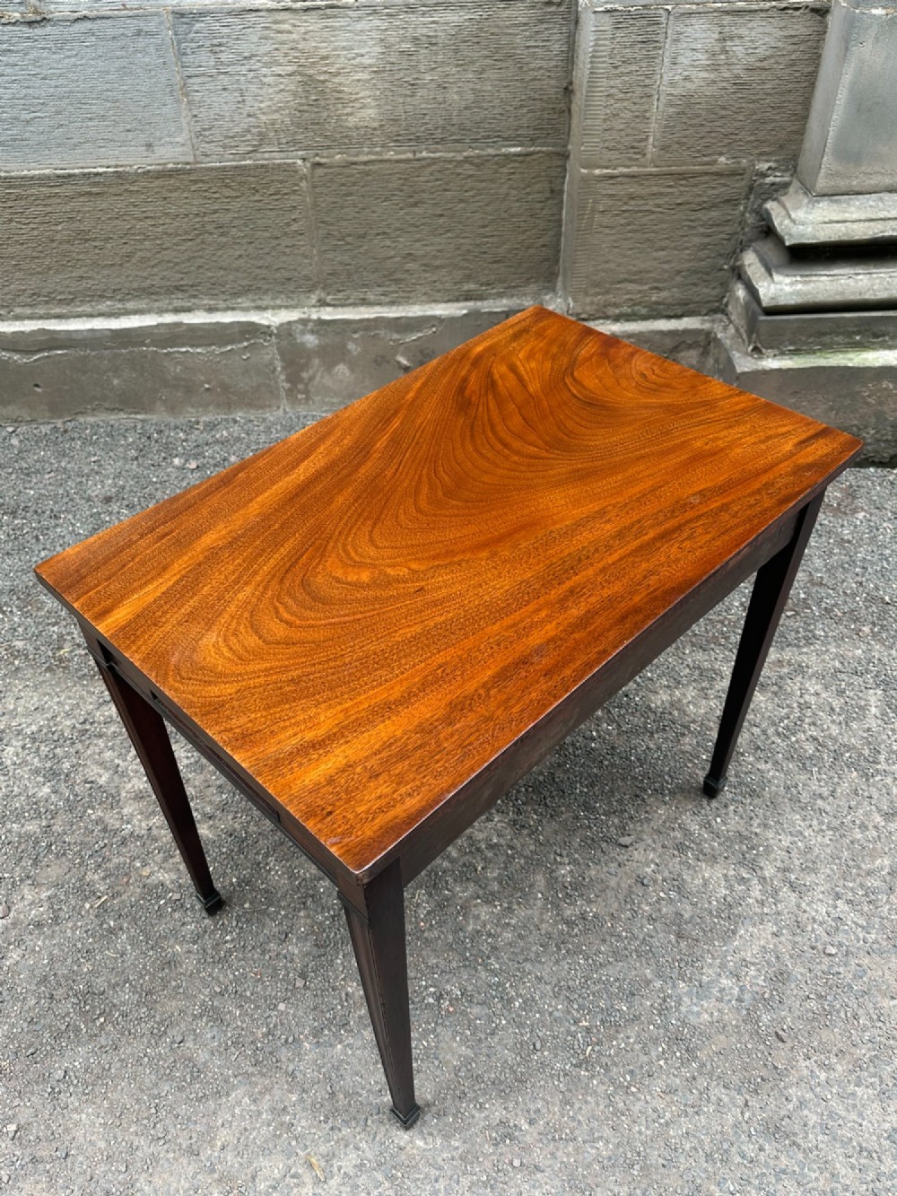 A George III mahogany side table with tapered legs, a flame mahogany veneered frieze, and a brass drawer pull. View IX