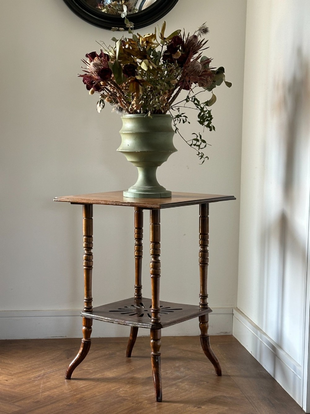 An Anglo-Japanese two-tier wooden occasional table featuring turned spindle legs, a square top, and a pierced lower shelf.