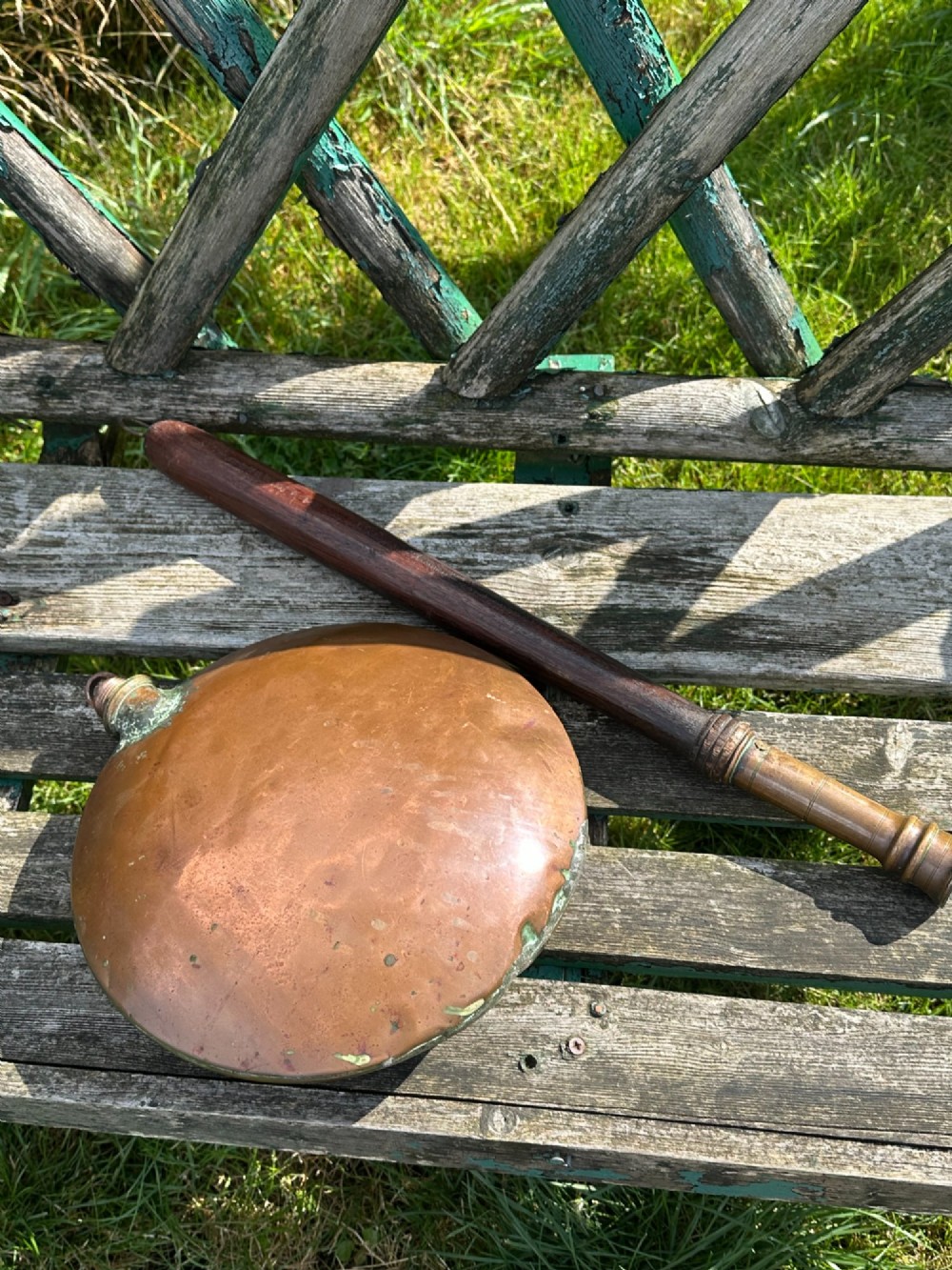 A circular Georgian copper moon flask with a threaded top loop, displayed alongside a separate turned dark oak handle. View V