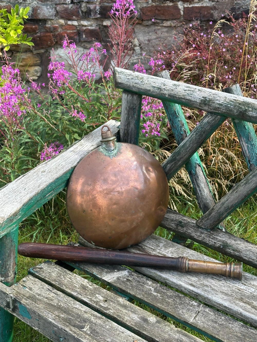 A circular Georgian copper moon flask with a threaded top loop, displayed alongside a separate turned dark oak handle.