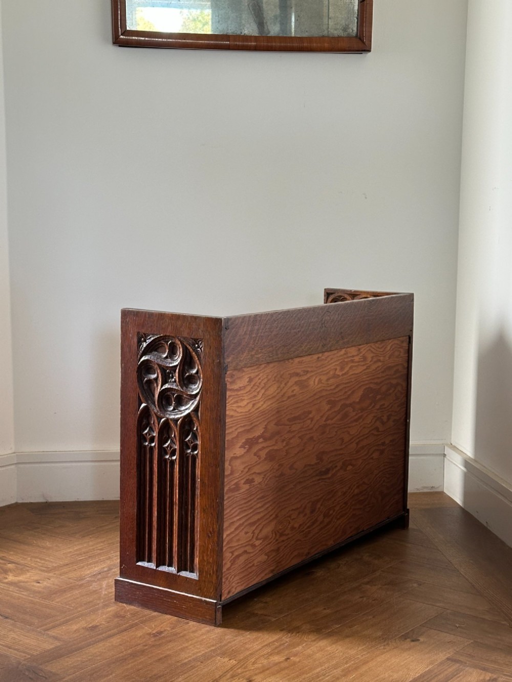 A low Arts and Crafts carved oak table cabinet featuring an open left compartment, a carved door on the right with foliate motifs, and a gallery top with carved rosettes. View II