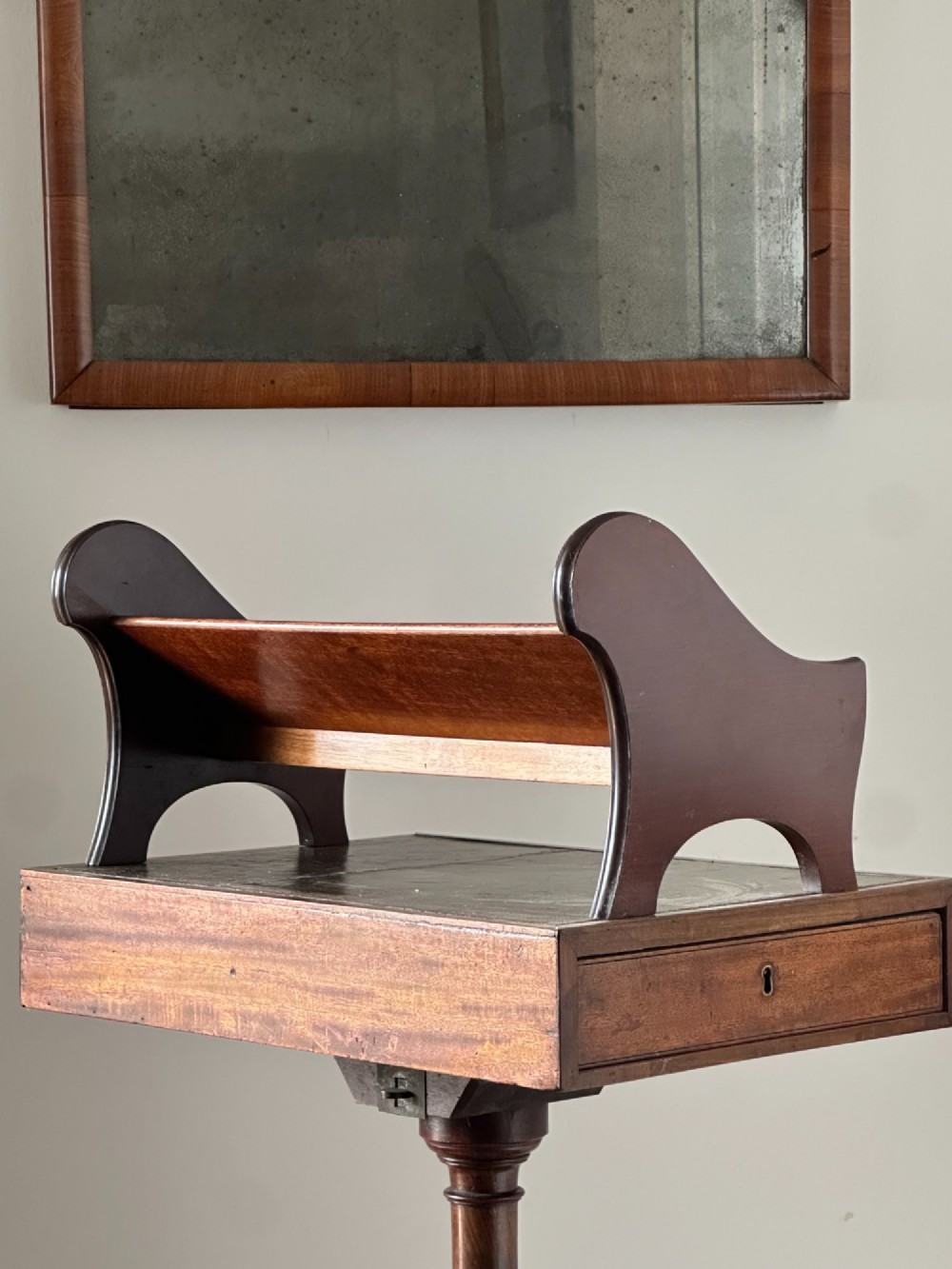 A late Victorian mahogany standing book trough featuring an upper angled trough, a small frieze drawer, turned pedestal stem, and tripod legs. View II