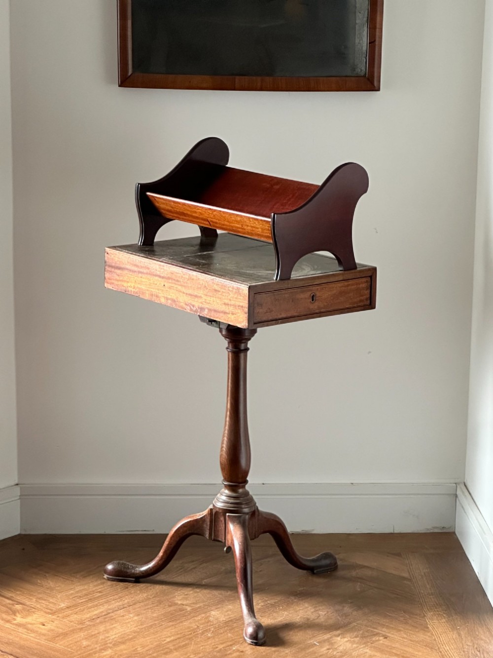A late Victorian mahogany standing book trough featuring an upper angled trough, a small frieze drawer, turned pedestal stem, and tripod legs. View IV