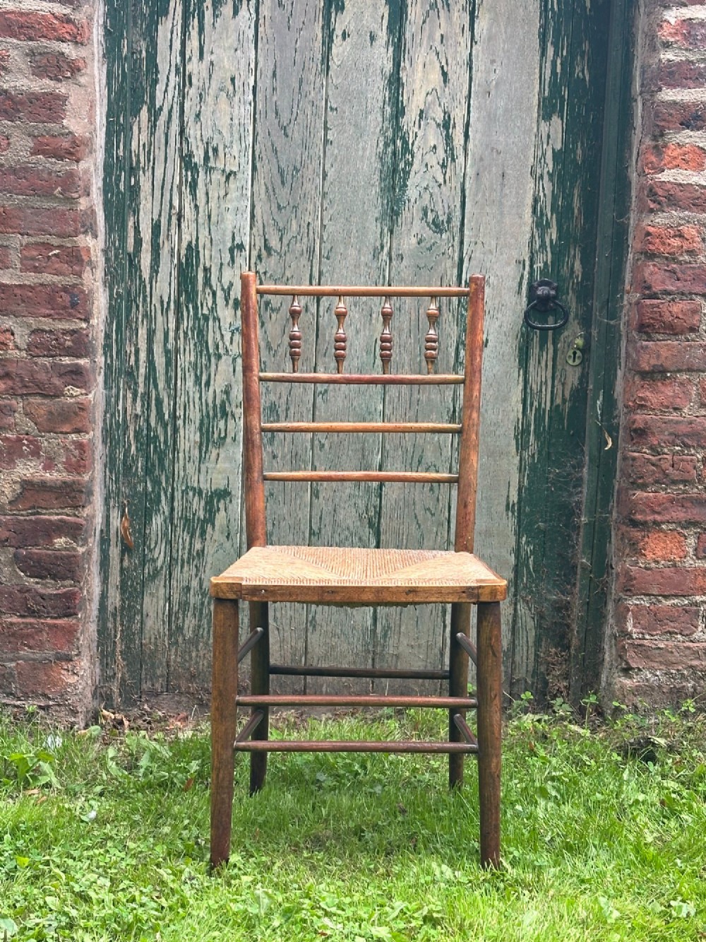 A set of four nineteenth-century beech Sussex chairs featuring turned spindle backrests and woven rush seats lined up outdoors. View VI
