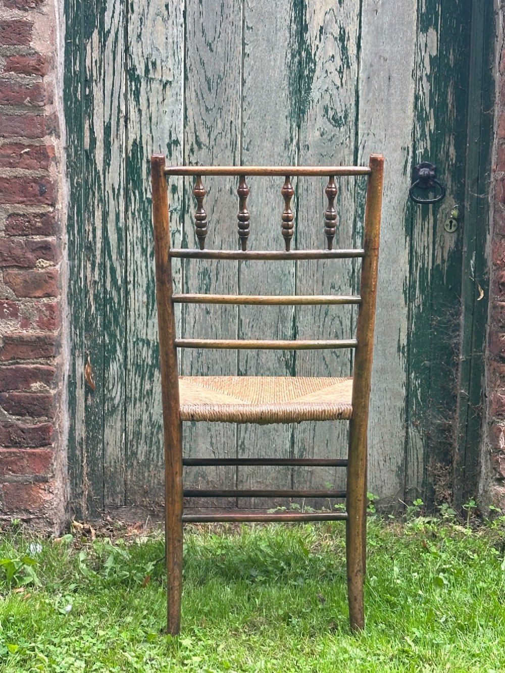 A set of four nineteenth-century beech Sussex chairs featuring turned spindle backrests and woven rush seats lined up outdoors. View VII