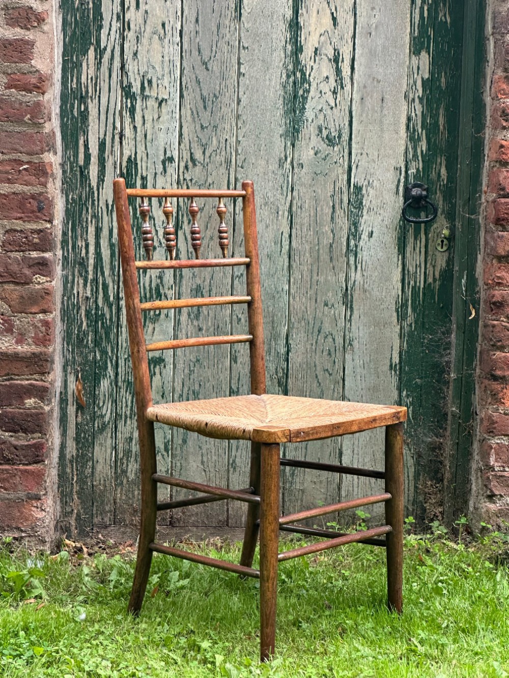 A set of four nineteenth-century beech Sussex chairs featuring turned spindle backrests and woven rush seats lined up outdoors. View VIII