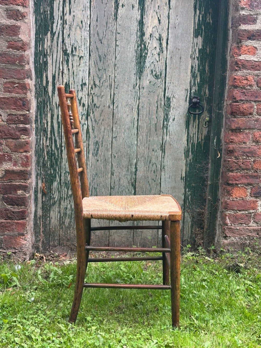 A set of four nineteenth-century beech Sussex chairs featuring turned spindle backrests and woven rush seats lined up outdoors. View IX