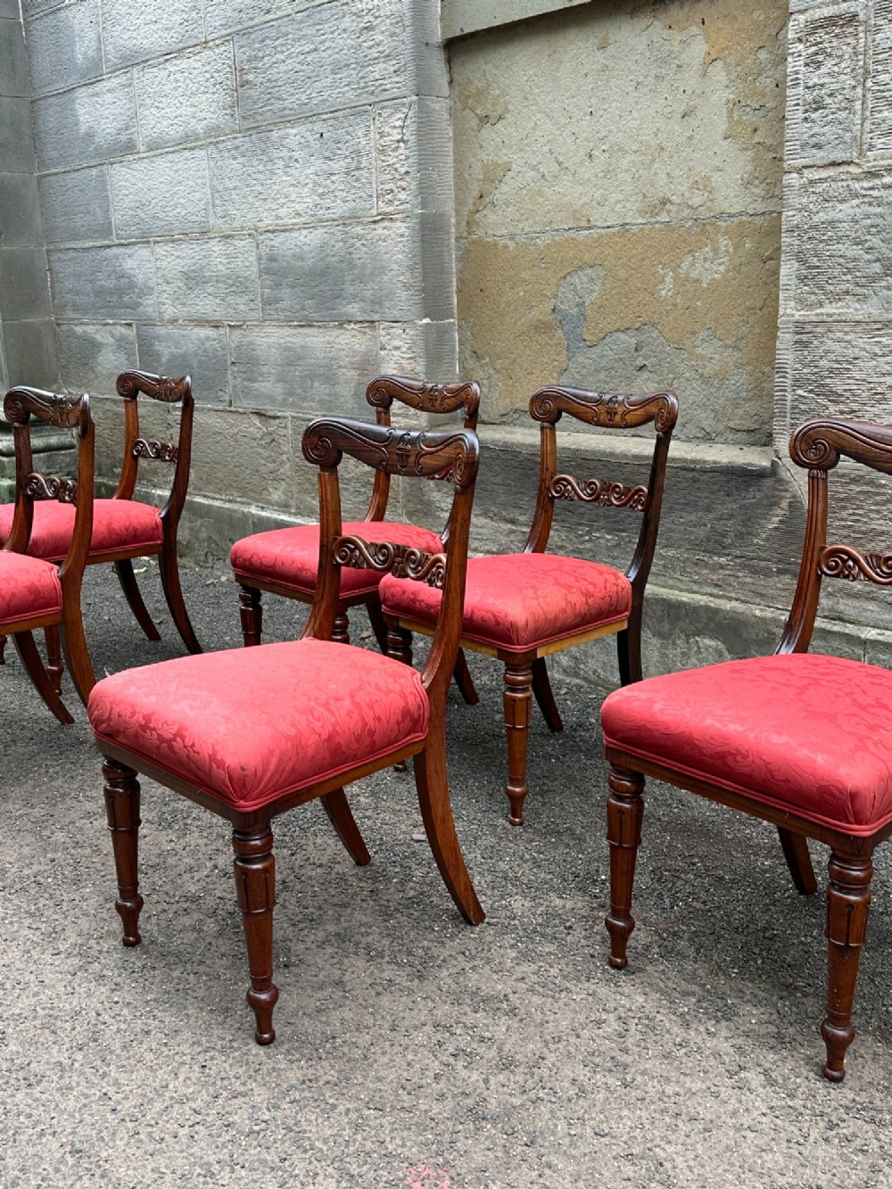 Set of six antique George IV rosewood dining chairs featuring carved top rails, horizontal back splats, turned front legs, and red upholstered seats. View II