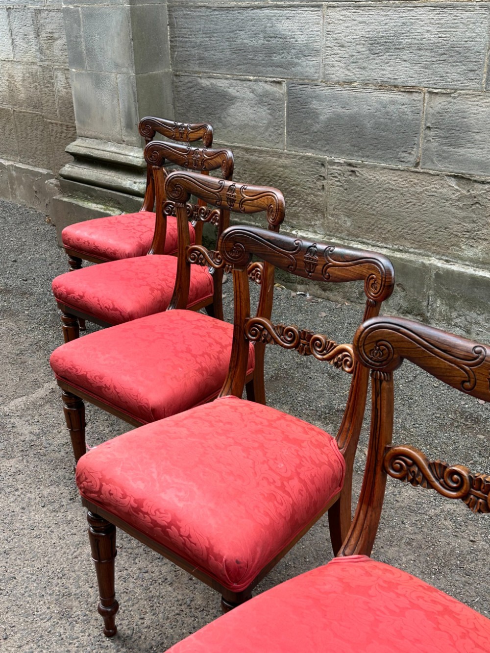 Set of six antique George IV rosewood dining chairs featuring carved top rails, horizontal back splats, turned front legs, and red upholstered seats. View III