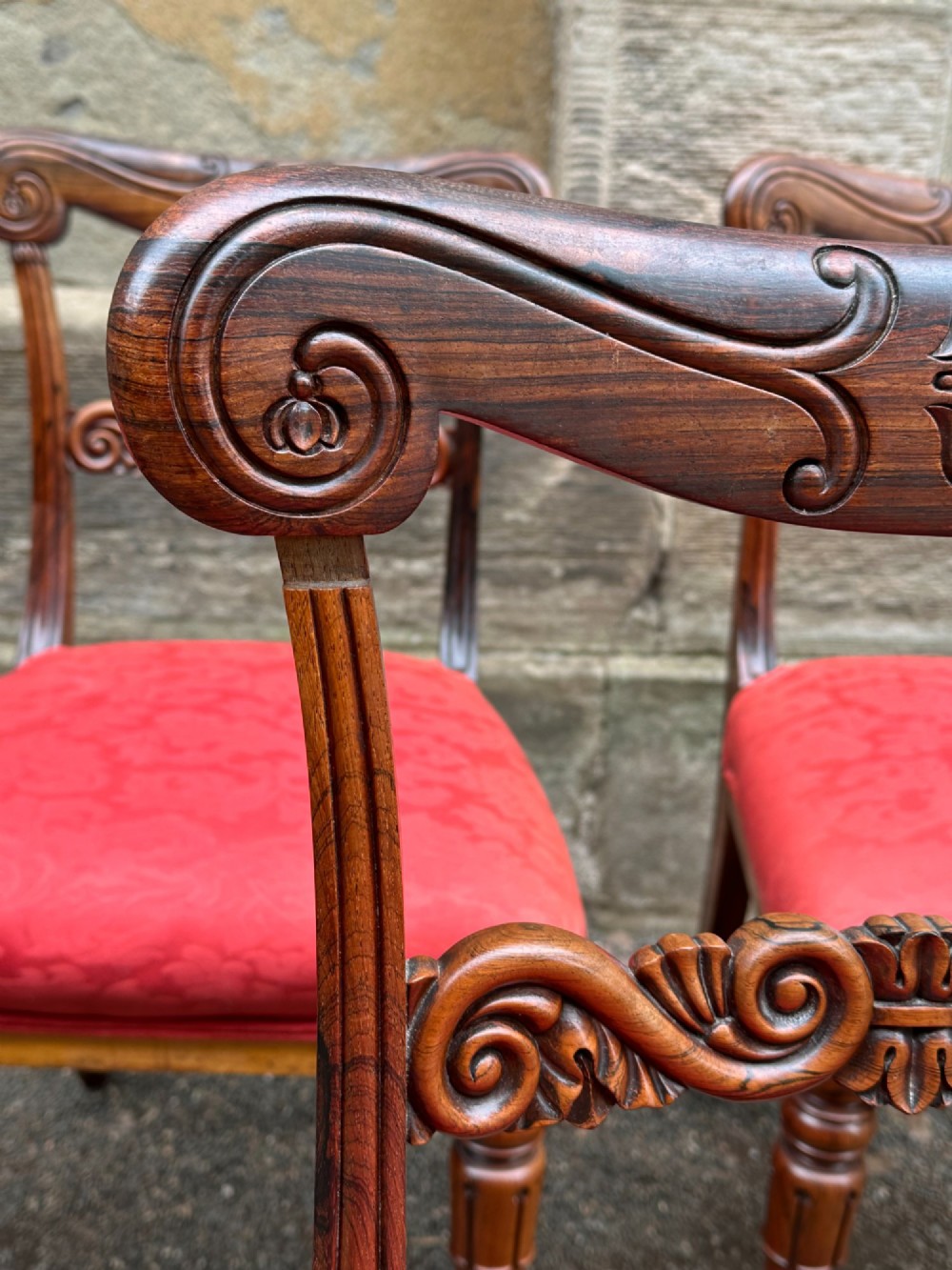 Set of six antique George IV rosewood dining chairs featuring carved top rails, horizontal back splats, turned front legs, and red upholstered seats. View IV