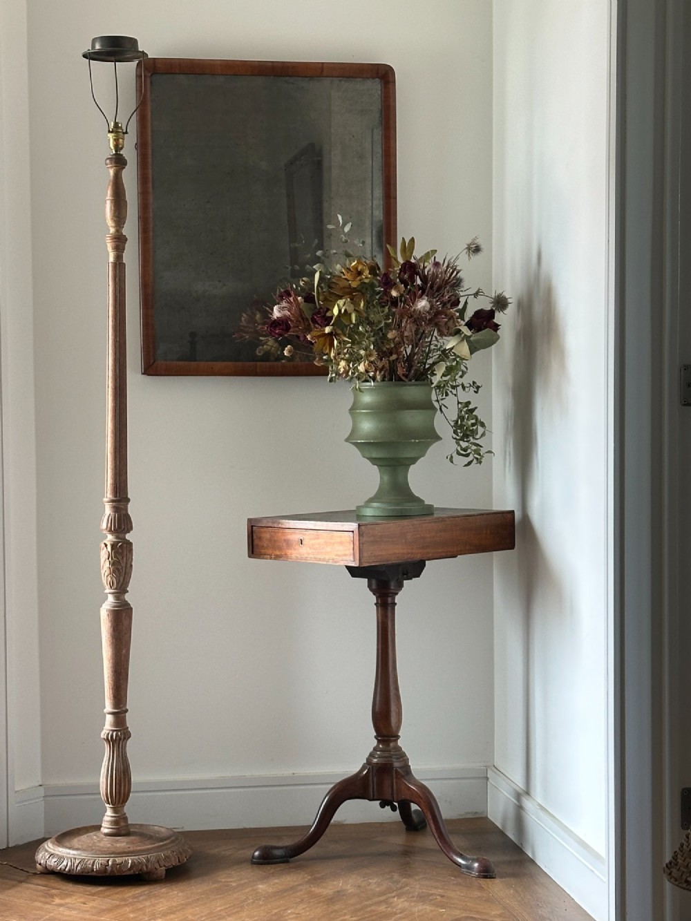 A carved limed oak floor lamp from the 1920s featuring a fluted column, leaf motifs, and a circular base.