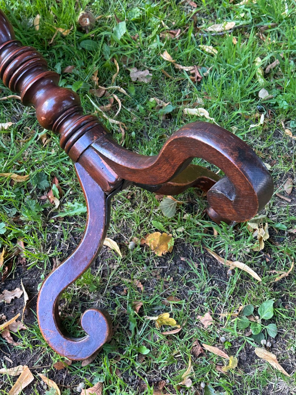 A George III mahogany tripod table featuring a circular top supported by a turned central stem and three scrolled legs. View V