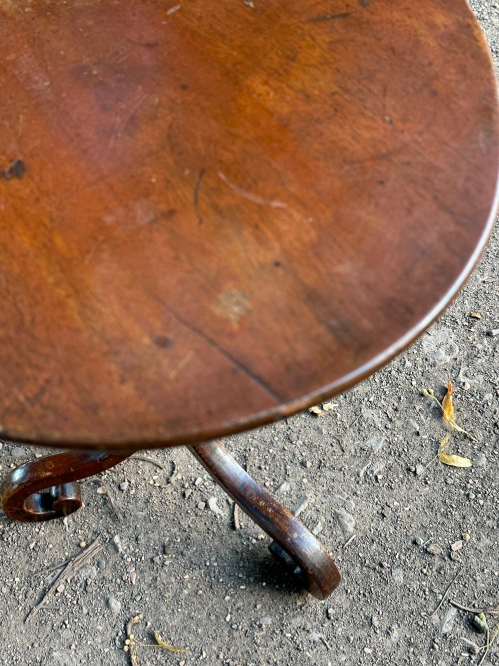 A George III mahogany tripod table featuring a circular top supported by a turned central stem and three scrolled legs. View VII