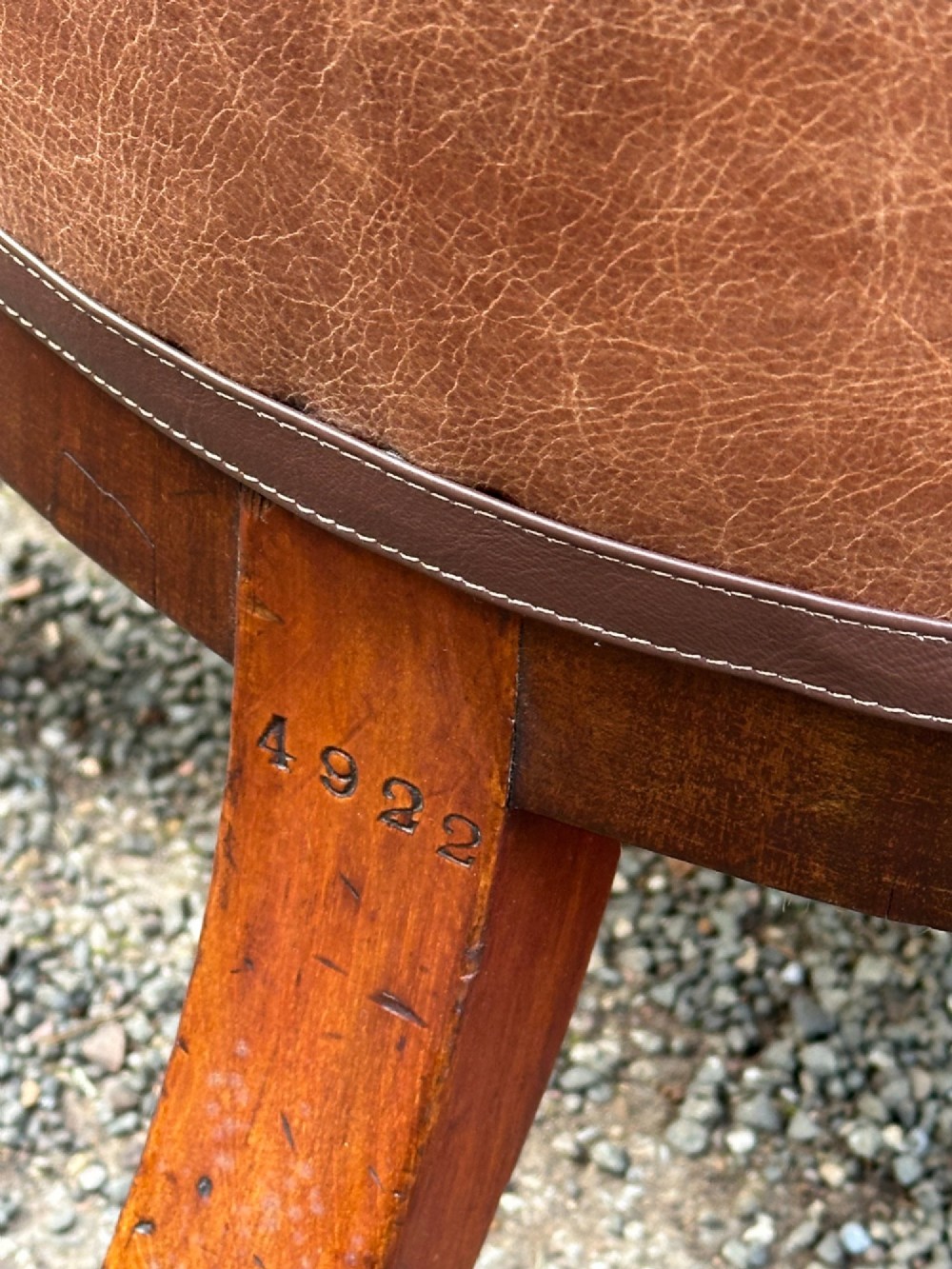 A pair of nineteenth-century Greek Revival mahogany armchairs upholstered in warm brown leather with turned front legs on castors and incised geometric detailing. View VI