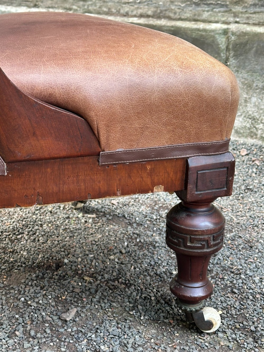 A pair of nineteenth-century Greek Revival mahogany armchairs upholstered in warm brown leather with turned front legs on castors and incised geometric detailing. View VII