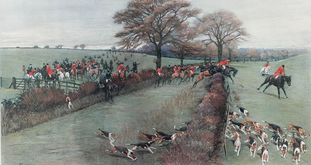 A panoramic antique colour print depicting a fox hunt in full pursuit across a green countryside landscape with riders jumping a hedge and hounds running in the foreground.