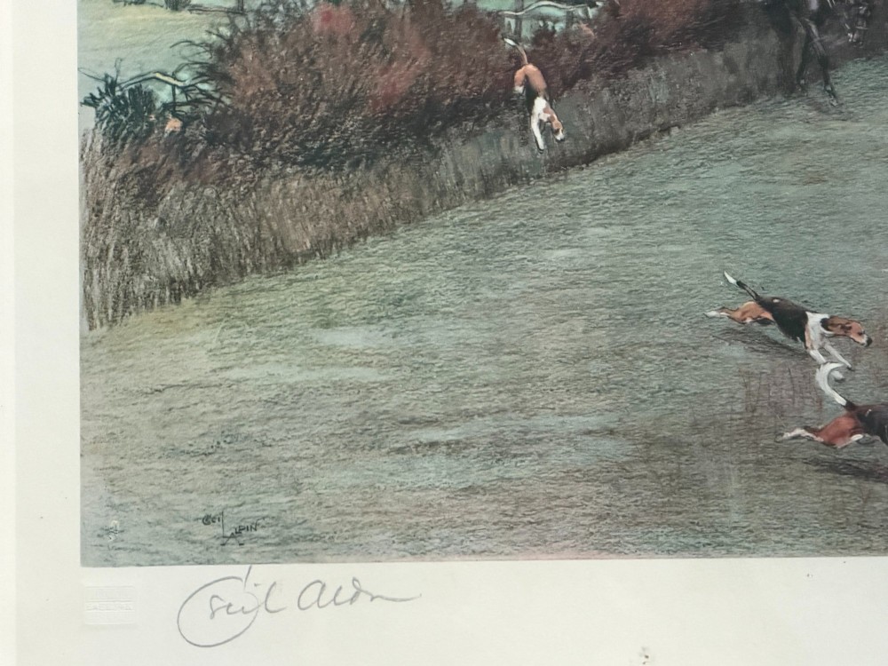 A panoramic antique colour print depicting a fox hunt in full pursuit across a green countryside landscape with riders jumping a hedge and hounds running in the foreground. View III