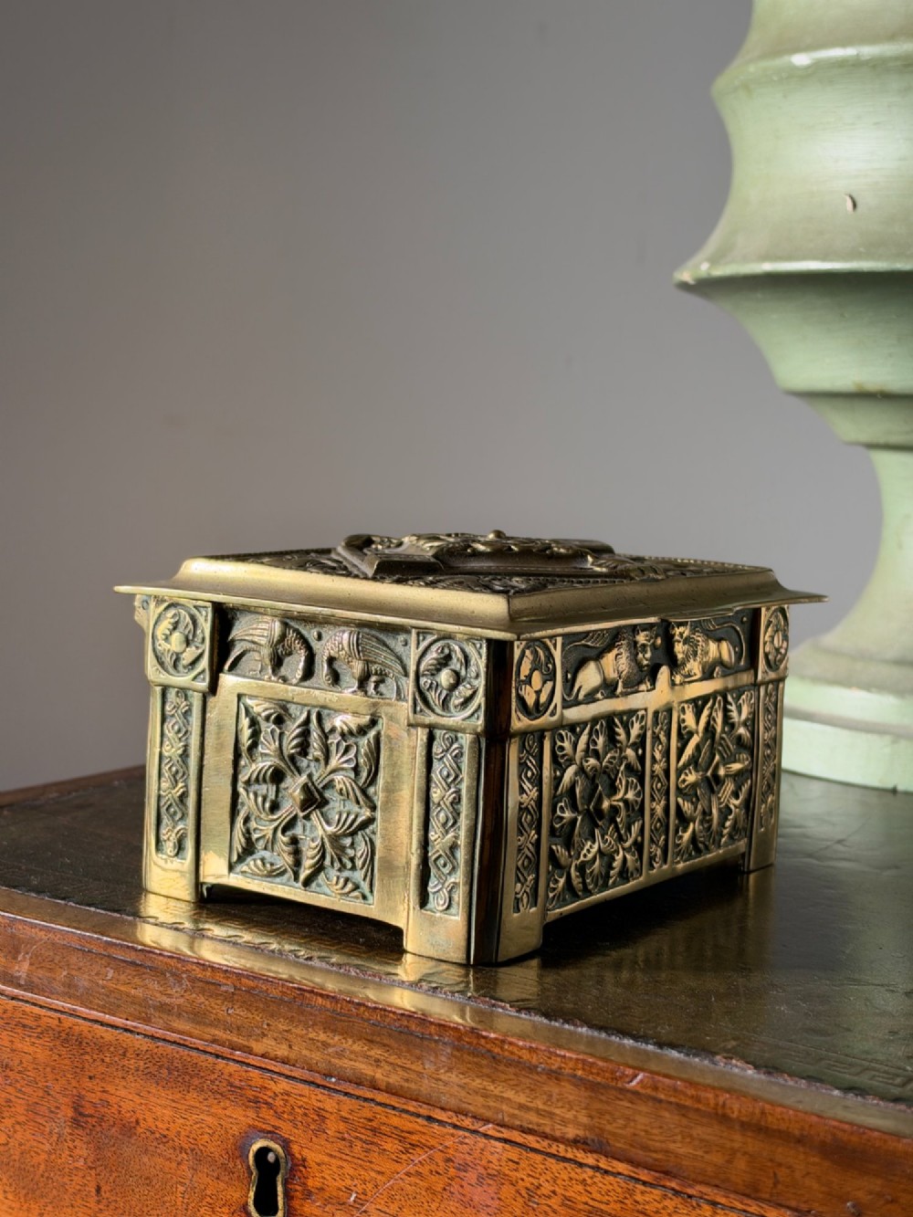 A nineteenth-century rectangular cast brass casket featuring detailed relief ornamentation of animals, foliage, and geometric patterns. View V