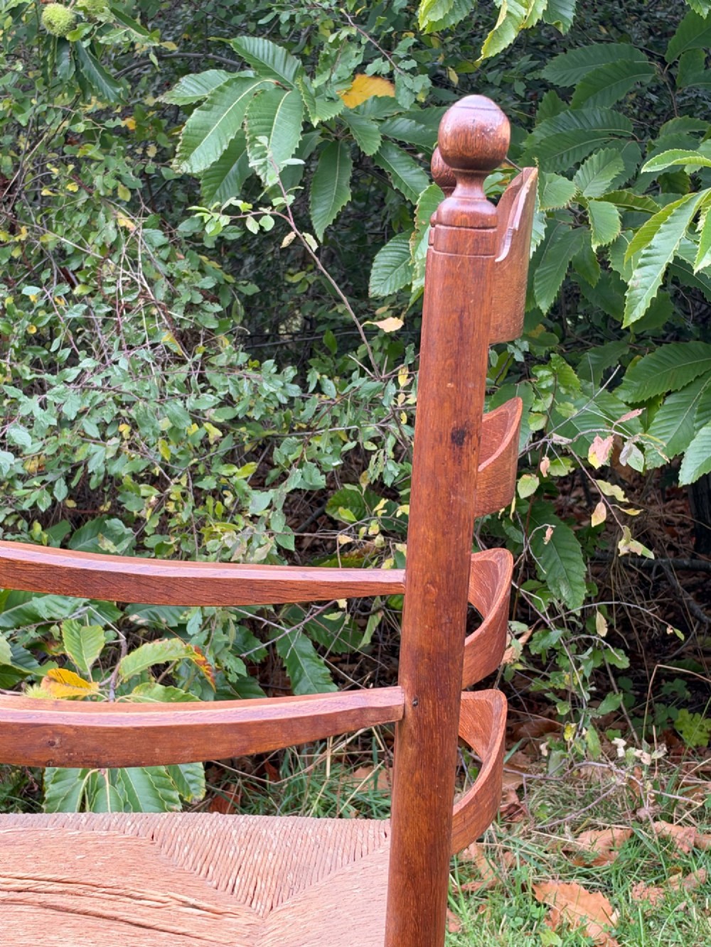 An early 20th-century Anglo-Indian armchair made of medium brown teak with a ladder back, turned front legs, shaped armrests, and a woven rush seat. View III