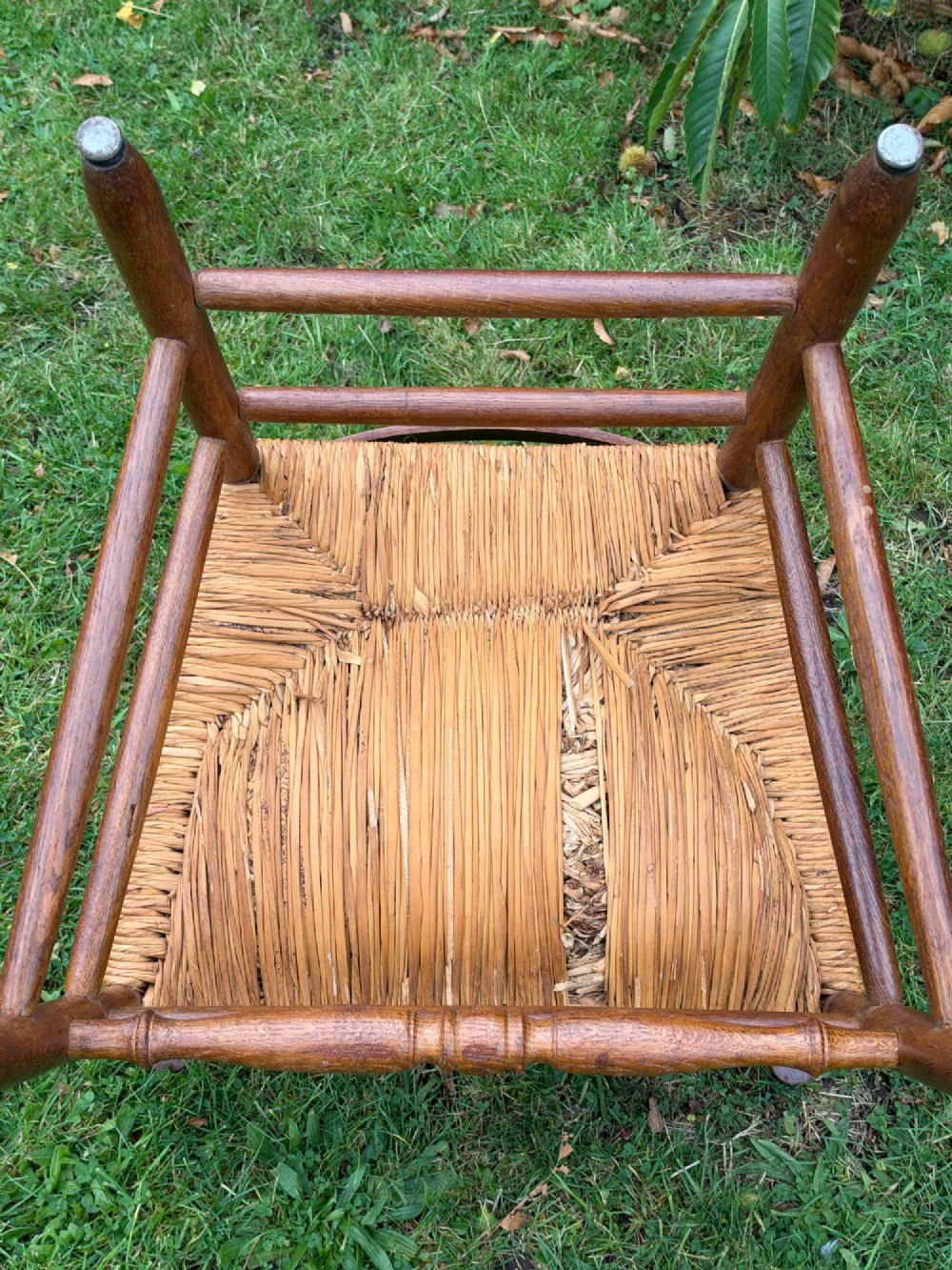 An early 20th-century Anglo-Indian armchair made of medium brown teak with a ladder back, turned front legs, shaped armrests, and a woven rush seat. View IV