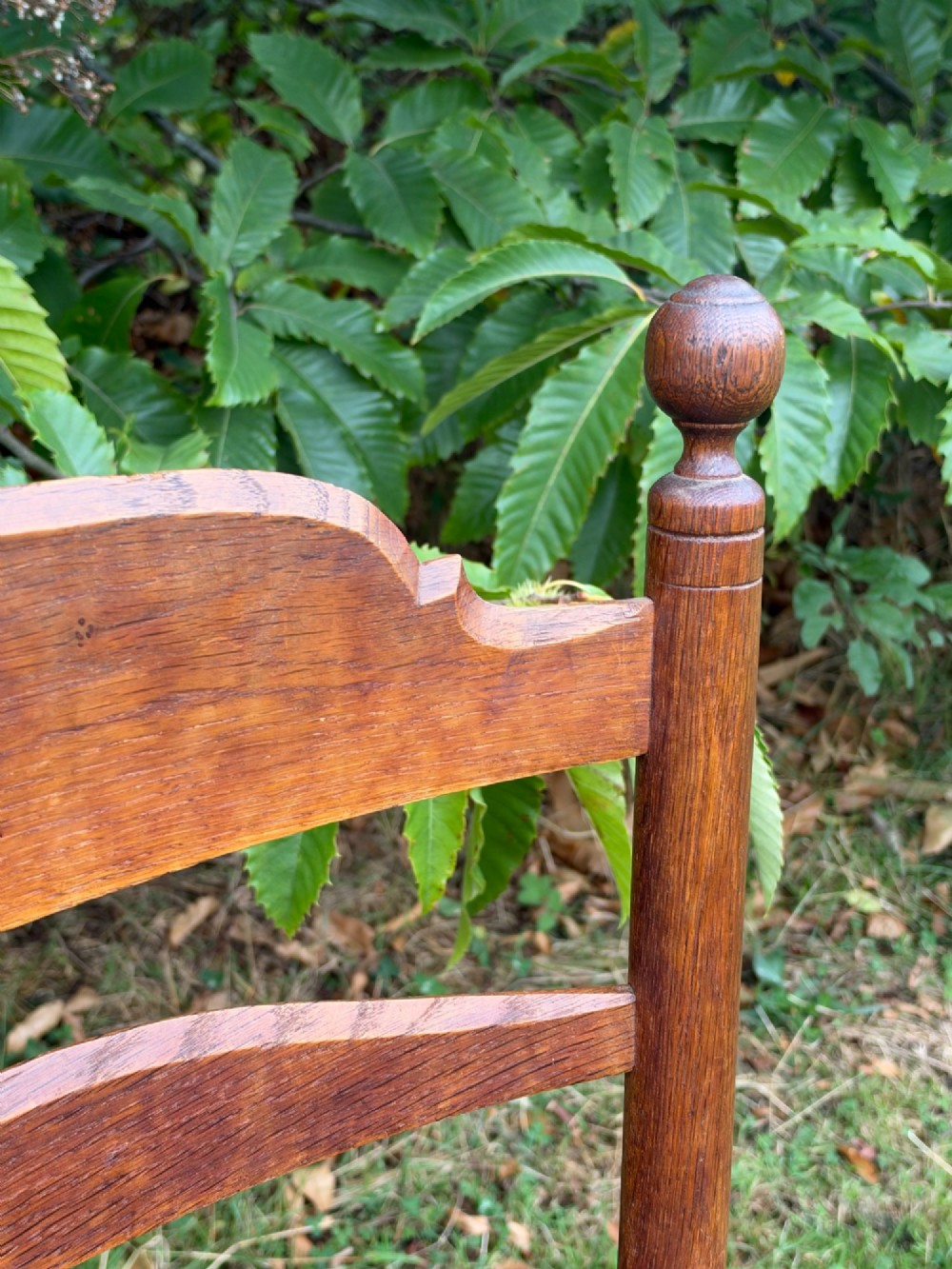 An early 20th-century Anglo-Indian armchair made of medium brown teak with a ladder back, turned front legs, shaped armrests, and a woven rush seat. View VI