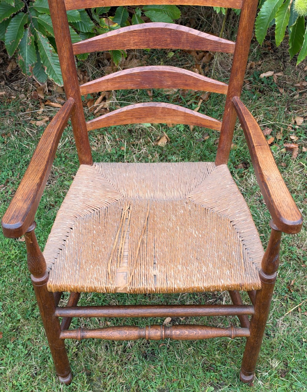 An early 20th-century Anglo-Indian armchair made of medium brown teak with a ladder back, turned front legs, shaped armrests, and a woven rush seat. View VII