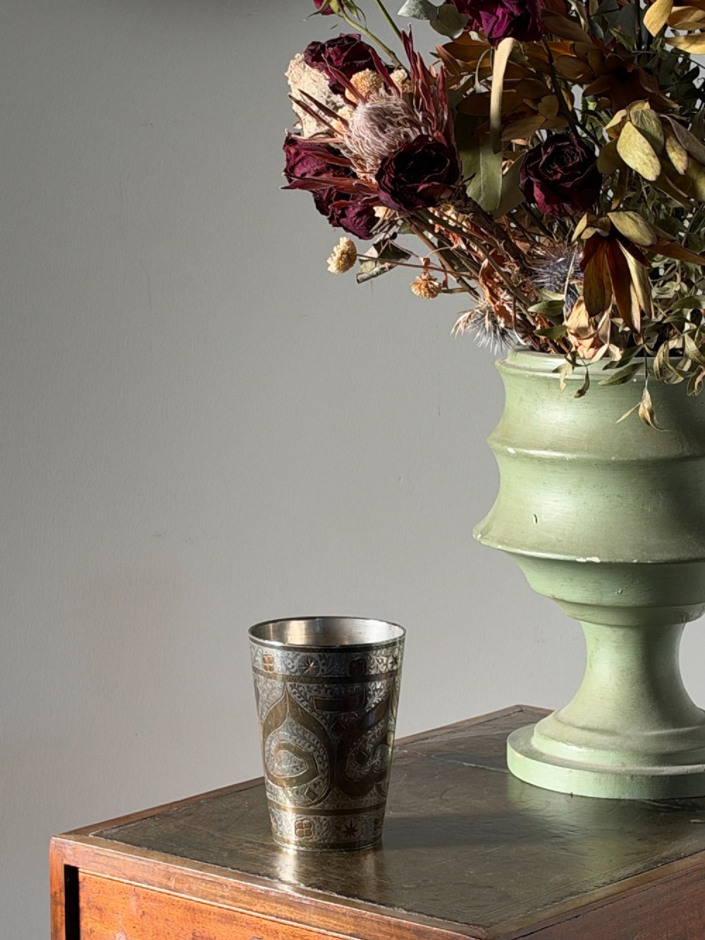 A tapered white metal beaker featuring detailed hand-engraved foliage motifs, star emblems, and a tarnished patina. View II
