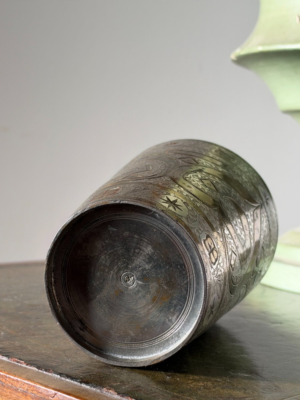 A tapered white metal beaker featuring detailed hand-engraved foliage motifs, star emblems, and a tarnished patina. View VII