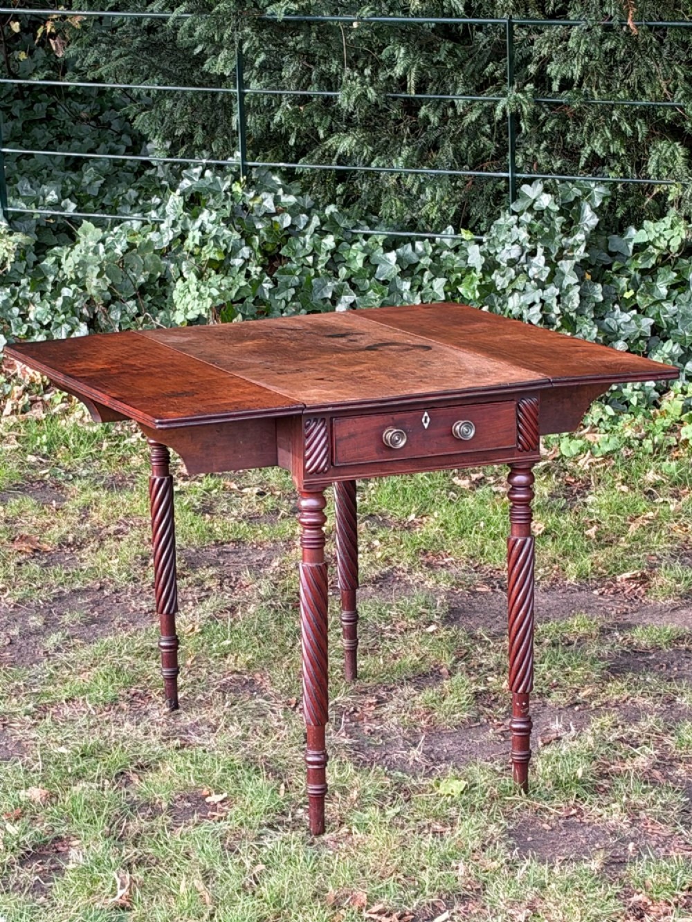 A George IV mahogany drop-leaf table featuring spiral turned legs, a single drawer with twin pull knobs, and two folding side leaves. View V