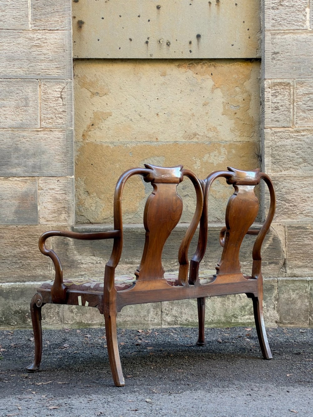 A late nineteenth-century George II style double chair-back settee in warm brown walnut and burr walnut with shepherd crook arms and an upholstered seat. View X