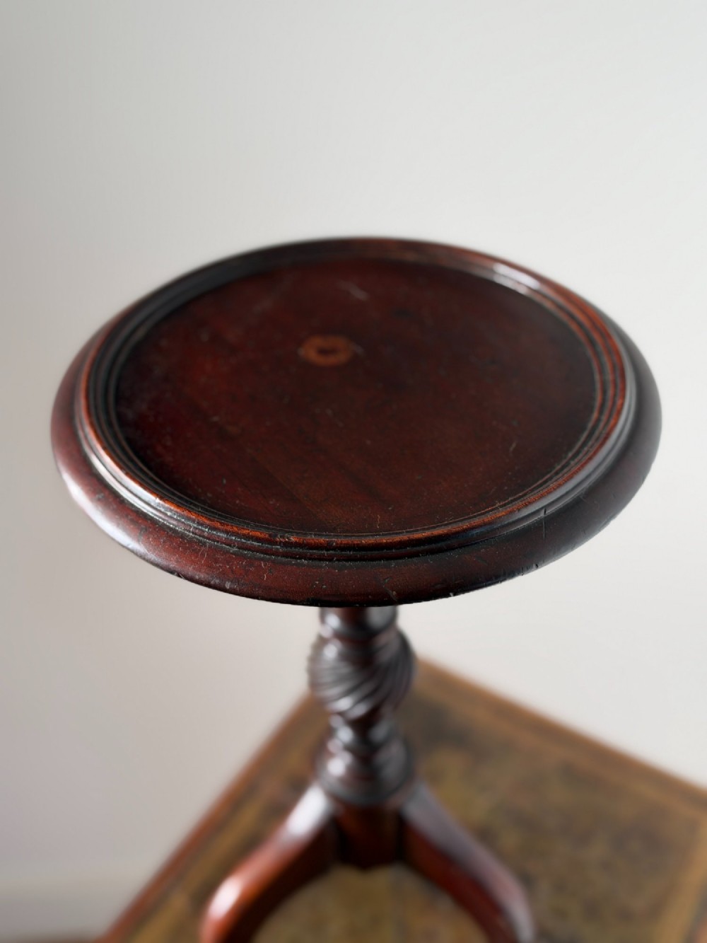 A late 19th-century George III style dark mahogany kettle stand with a circular dish top, spiral-carved baluster column, and tripod cabriole legs. View V