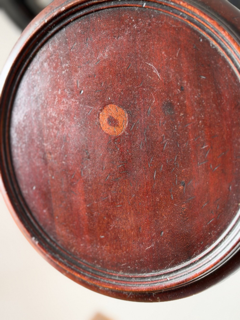 A late 19th-century George III style dark mahogany kettle stand with a circular dish top, spiral-carved baluster column, and tripod cabriole legs. View VI