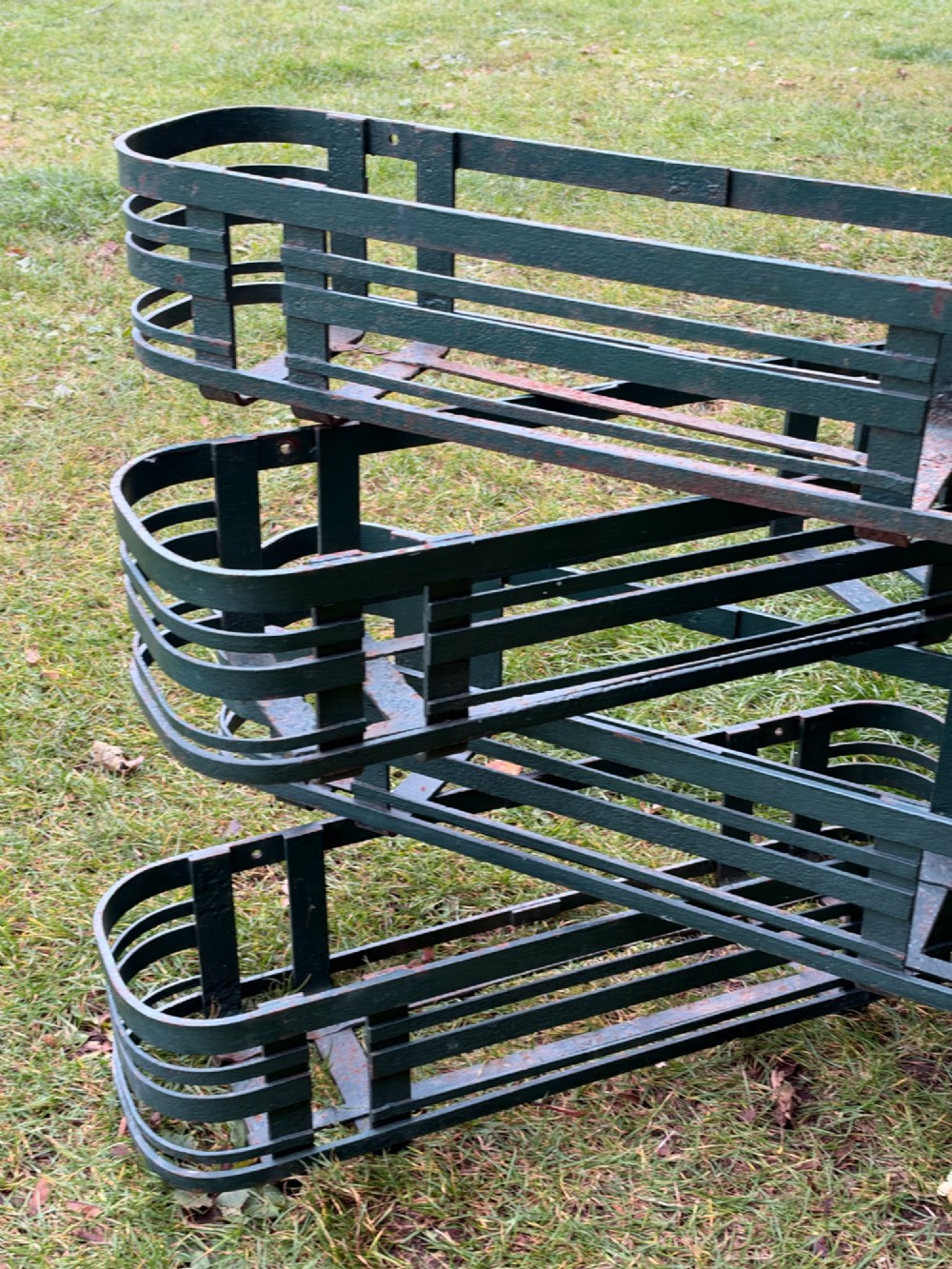 A set of four dark green painted iron strapwork window planters with rounded ends stacked outdoors. View V