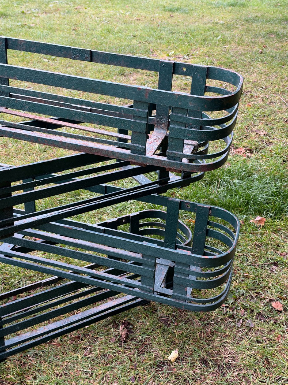A set of four dark green painted iron strapwork window planters with rounded ends stacked outdoors. View VI