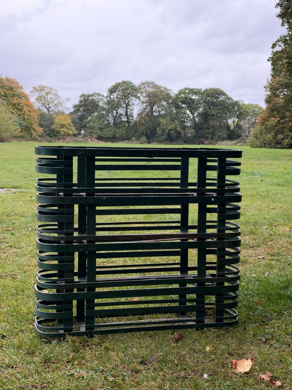A set of four dark green painted iron strapwork window planters with rounded ends stacked outdoors. View VII