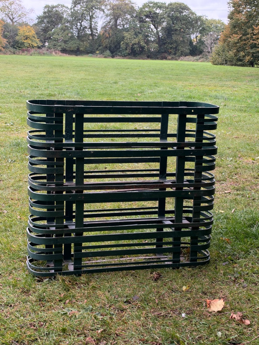A set of four dark green painted iron strapwork window planters with rounded ends stacked outdoors. View VIII