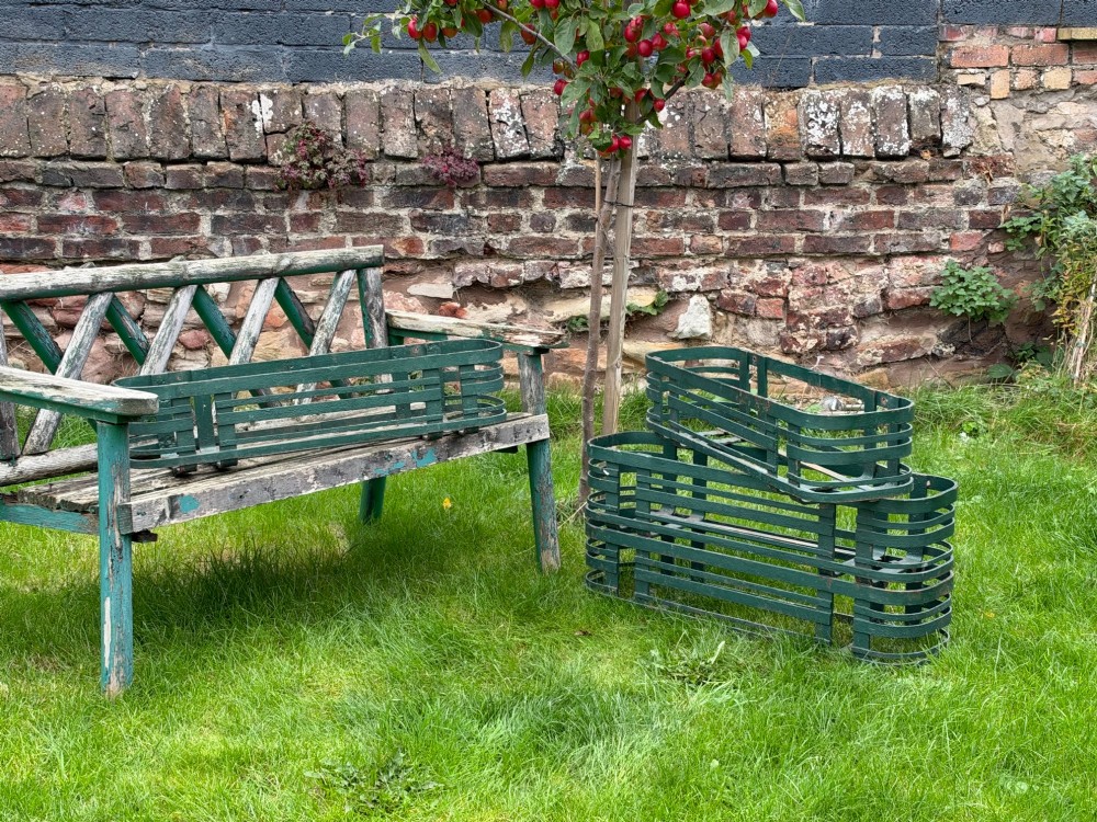 A set of four dark green painted iron strapwork window planters with rounded ends stacked outdoors. View IX