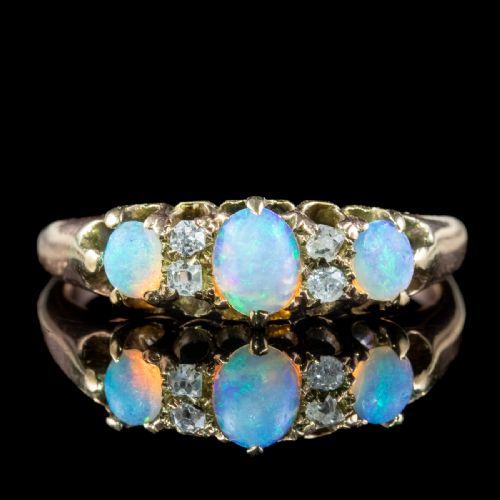 fig 2. An antique Victorian gold ring set with three oval cabochon opals and four small diamonds in a carved scroll gallery.