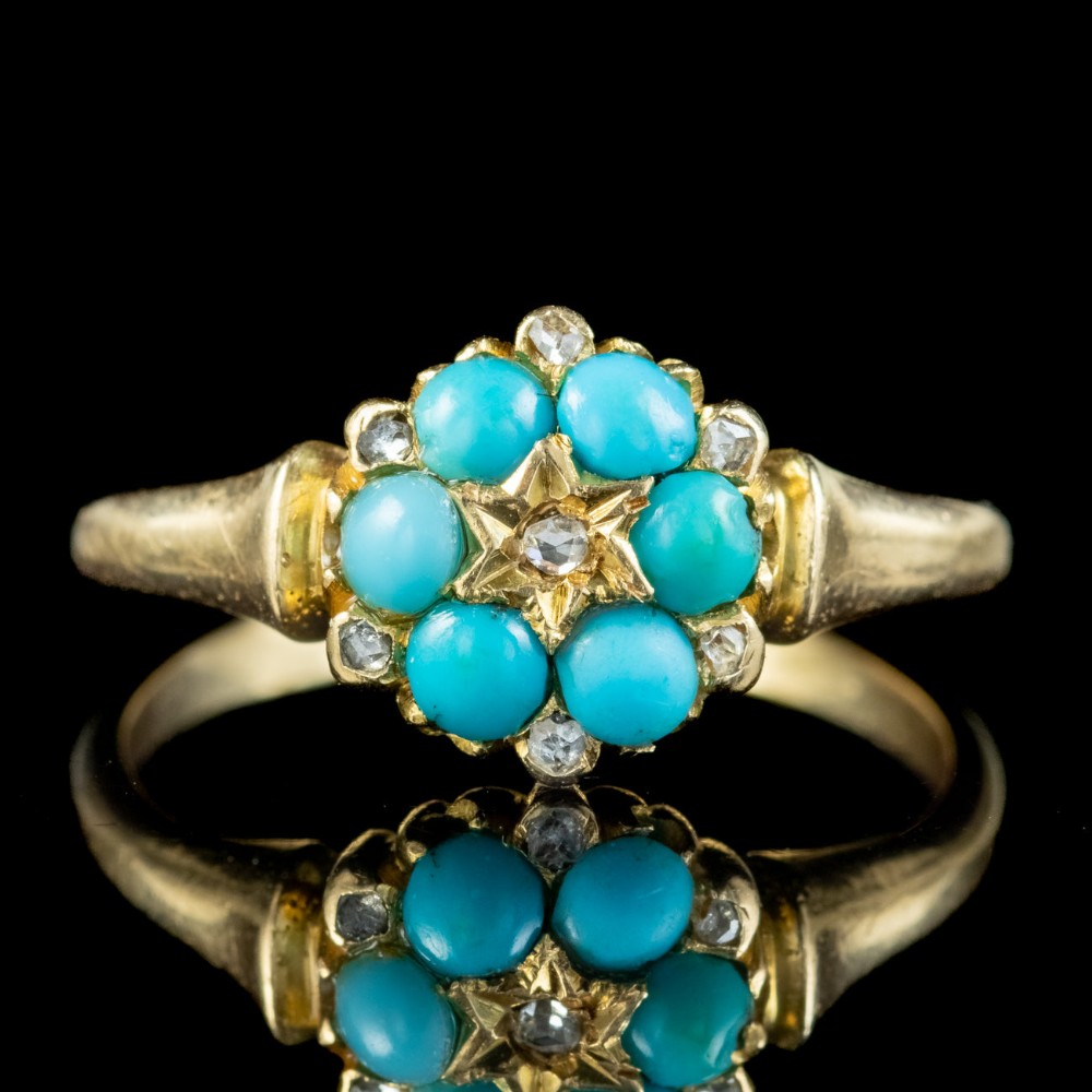 A Victorian gold ring featuring a floral cluster of bright blue turquoise cabochons surrounding a star-set central diamond.